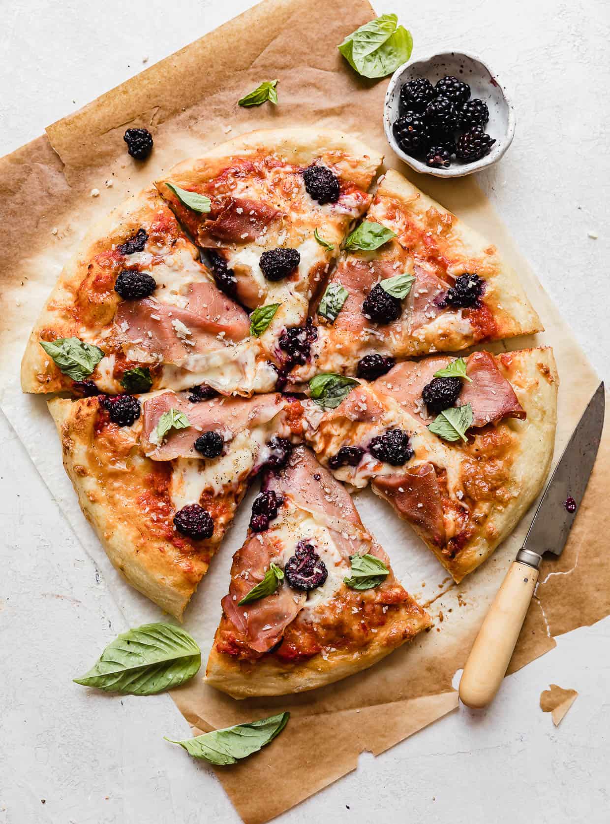 Blackberry Pizza topped with fresh basil on a white background.