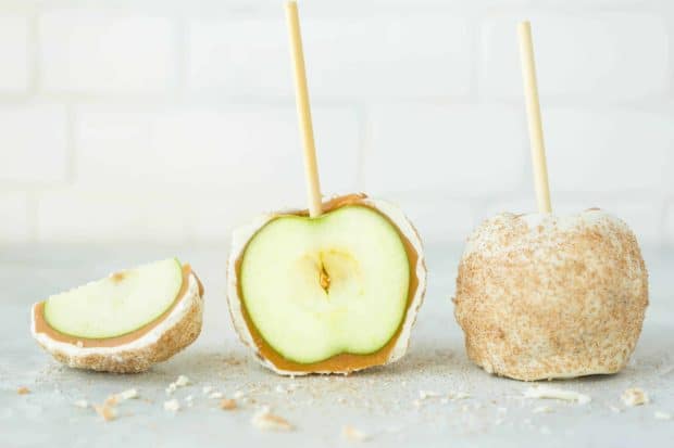 Caramel and white chocolate coated green apples against a white background.