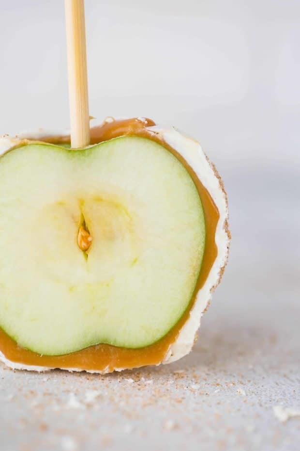 A caramel and white chocolate coated green apple sliced in half.