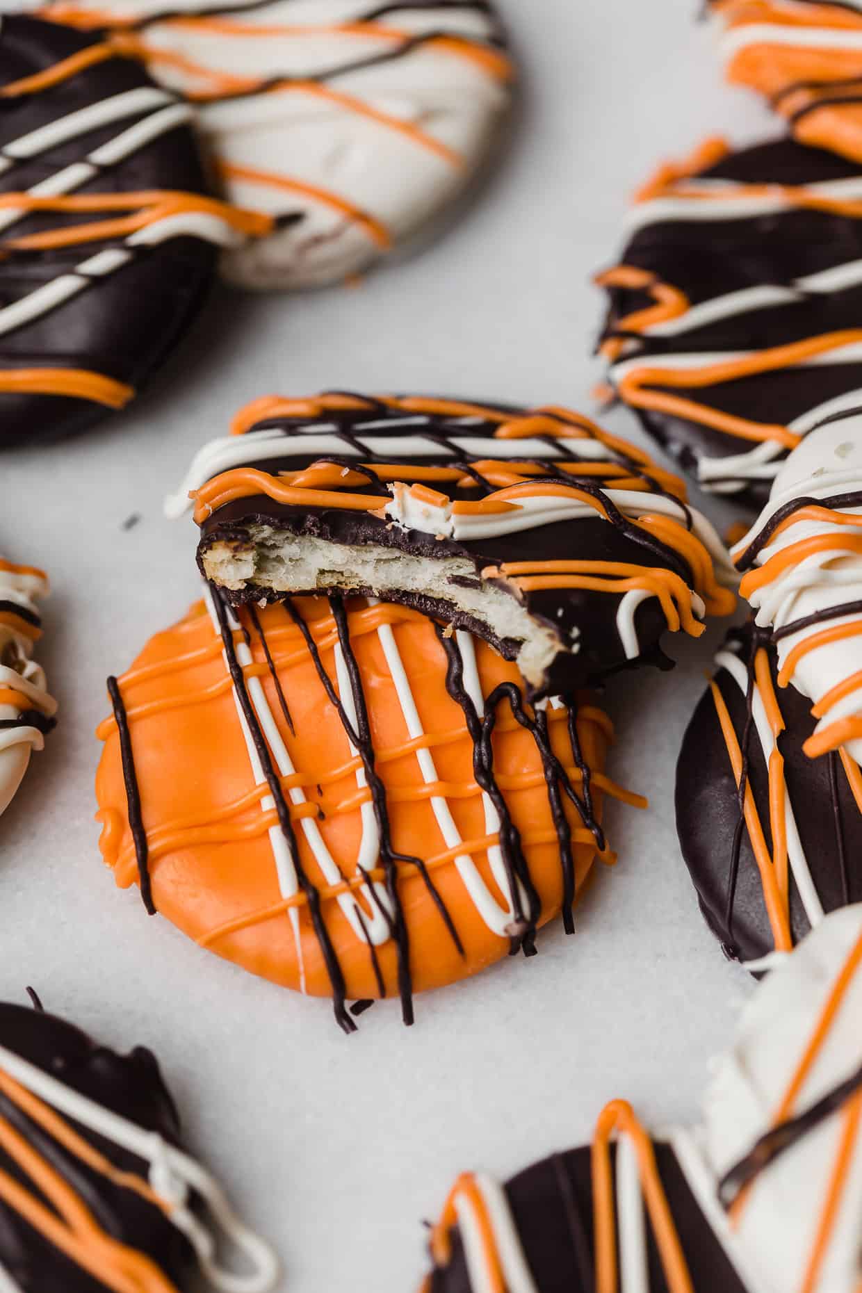 A bite taken out of a Halloween Cracker that's covered with black, orange, and white melted chocolate.