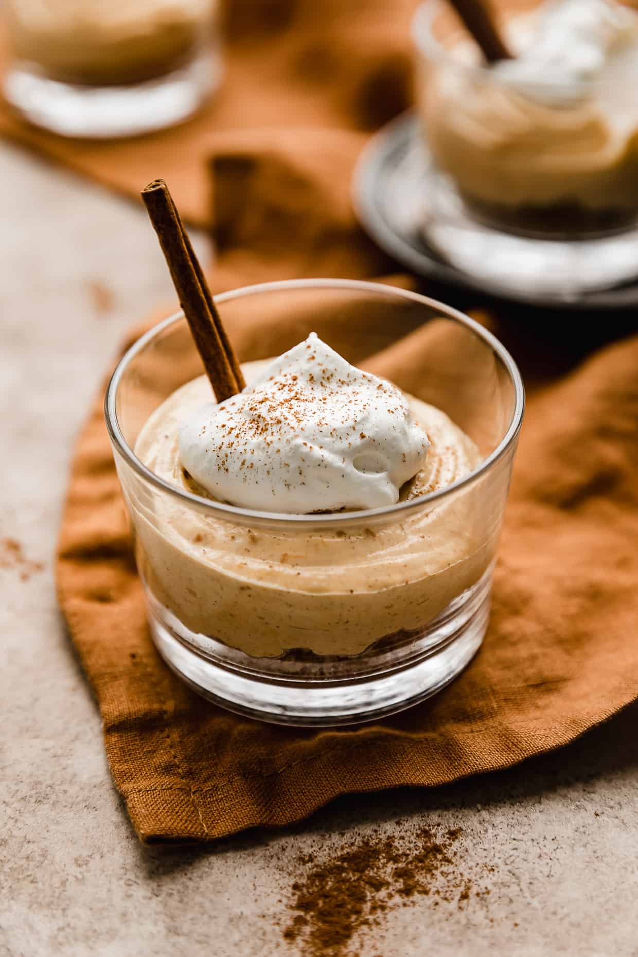 Mini No-Bake Pumpkin Cheesecakes topped with whipped cream in a small glass cup.