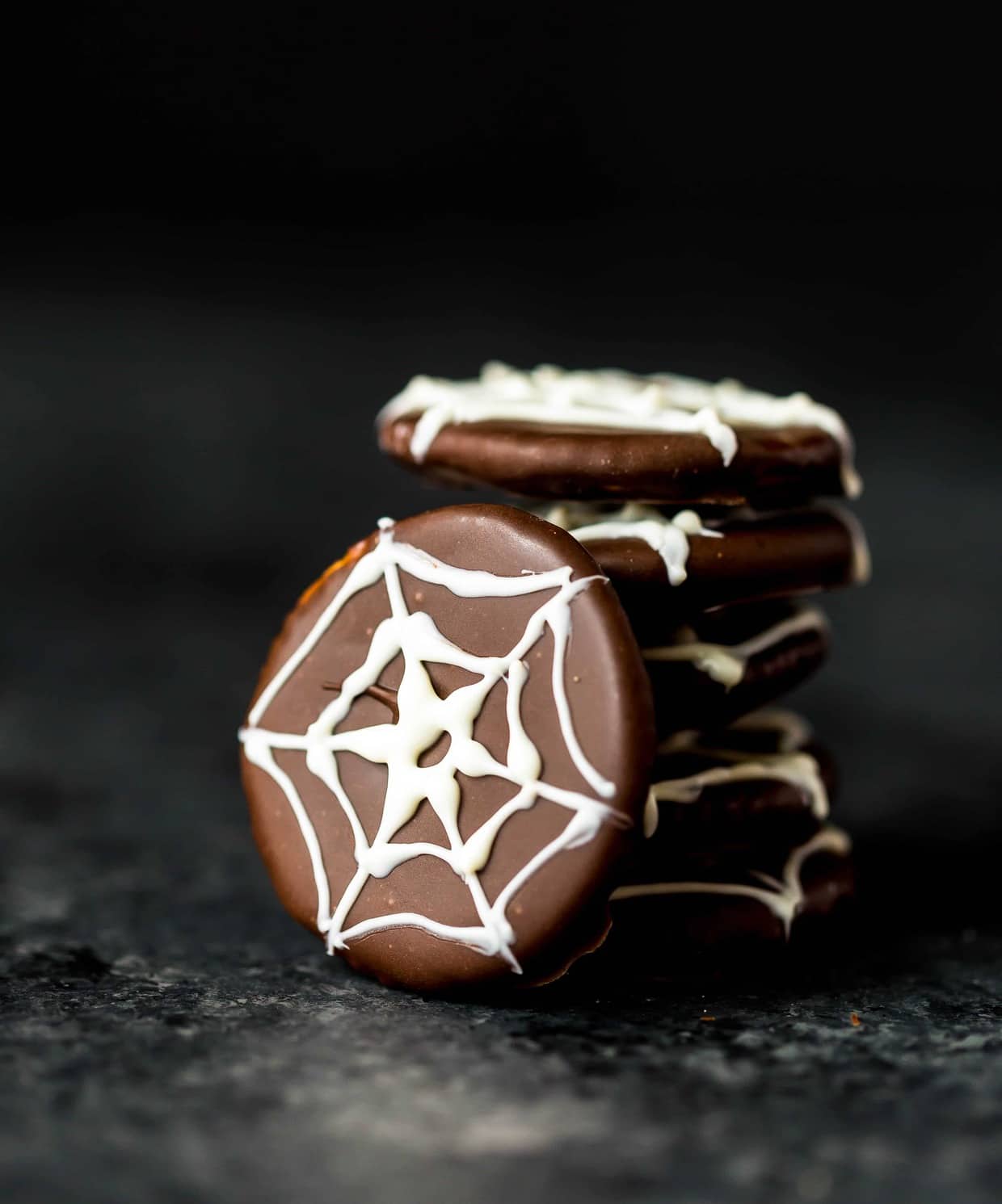 Chocolate covered ritz crackers featuring a white chocolate spider web design on top of cracker.
