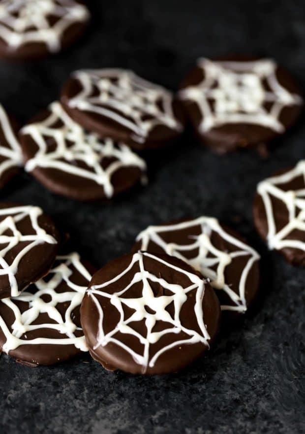 Chocolate covered ritz crackers with a white spider web design on the cracker.
