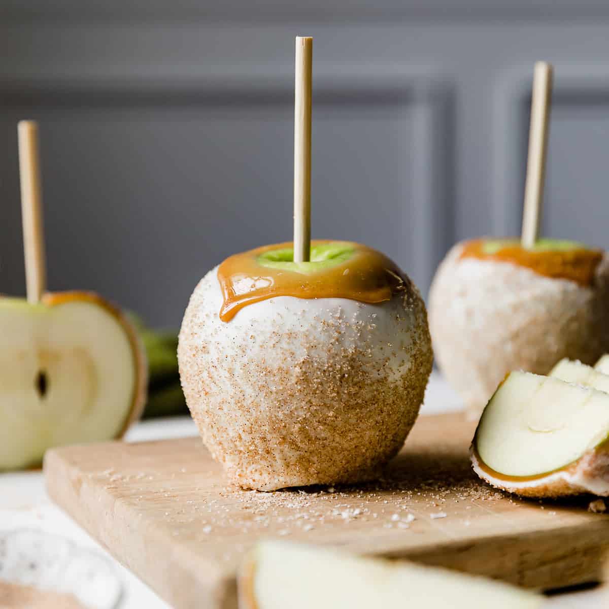 A white chocolate and caramel dipped Rocky Mountain Apple Pie Caramel Apple against a light gray background.