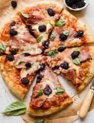 Blackberry Pizza topped with fresh basil and blackberries, sliced into 6 slices.