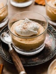Mini No-Bake Pumpkin Cheesecake in a glass cup, topped with whipped cream and pumpkin pie spice.