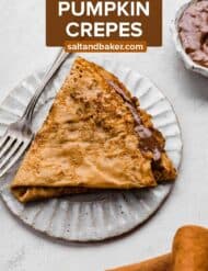 A nutella filled pumpkin crepe on a ruffled plate with the words, "The Best Pumpkin Crepes" in white text over the photo.