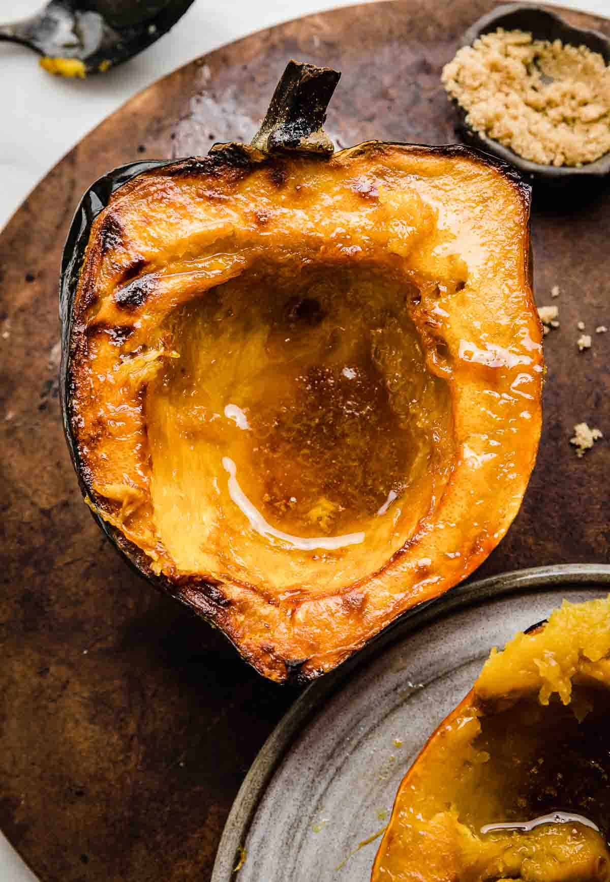 Roasted acorn squash with brown butter brown sugar mixture in the center of the squash.