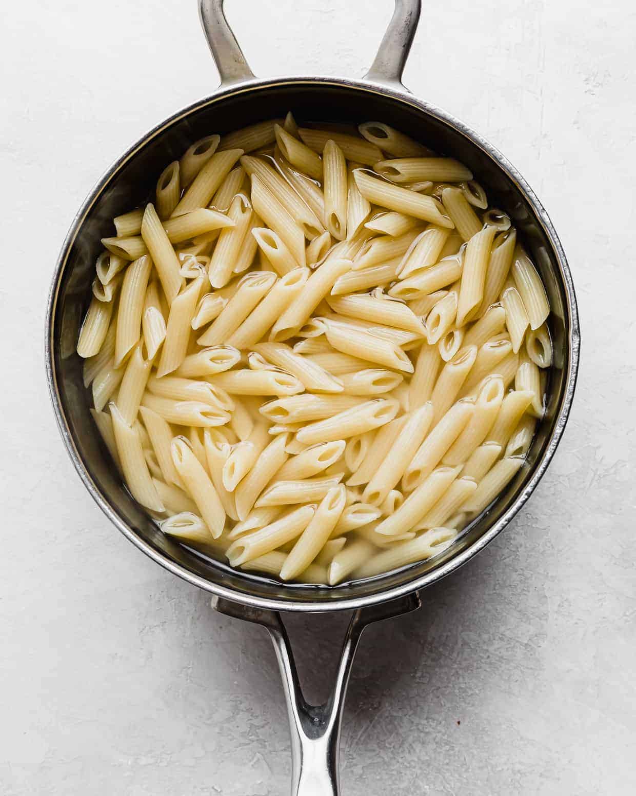 A saucepan with penne noodles in it. 