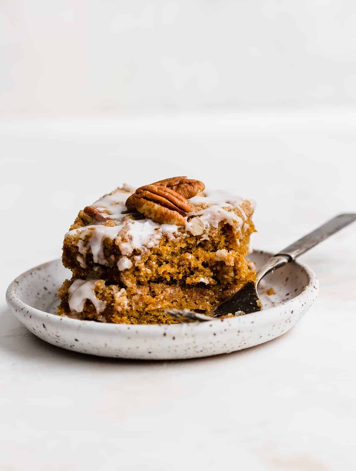 Pumpkin Coffee Cake on a white plate with some of the cake having been clearly eaten.