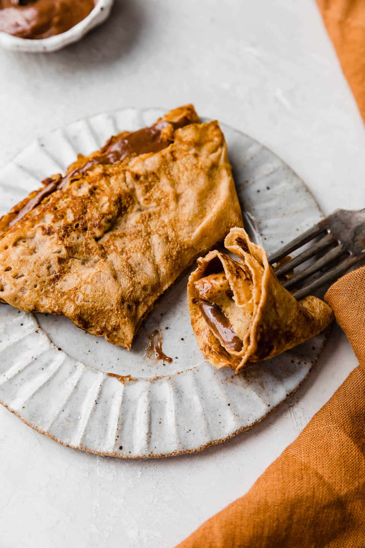 A Pumpkin Crepe filled with nutella whipped cream, cut into.