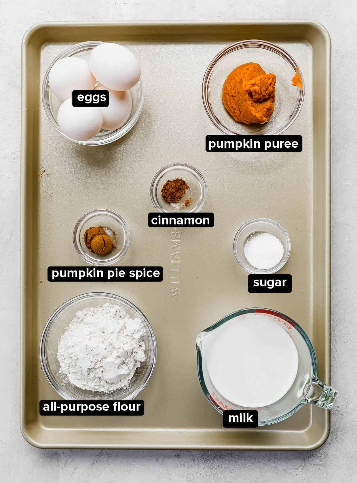Pumpkin Crepes ingredients portioned into glass bowls, on a gold baking sheet.