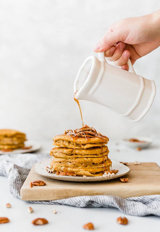 A stack of homemade pumpkin pancakes with homemade syrup drizzled overtop.