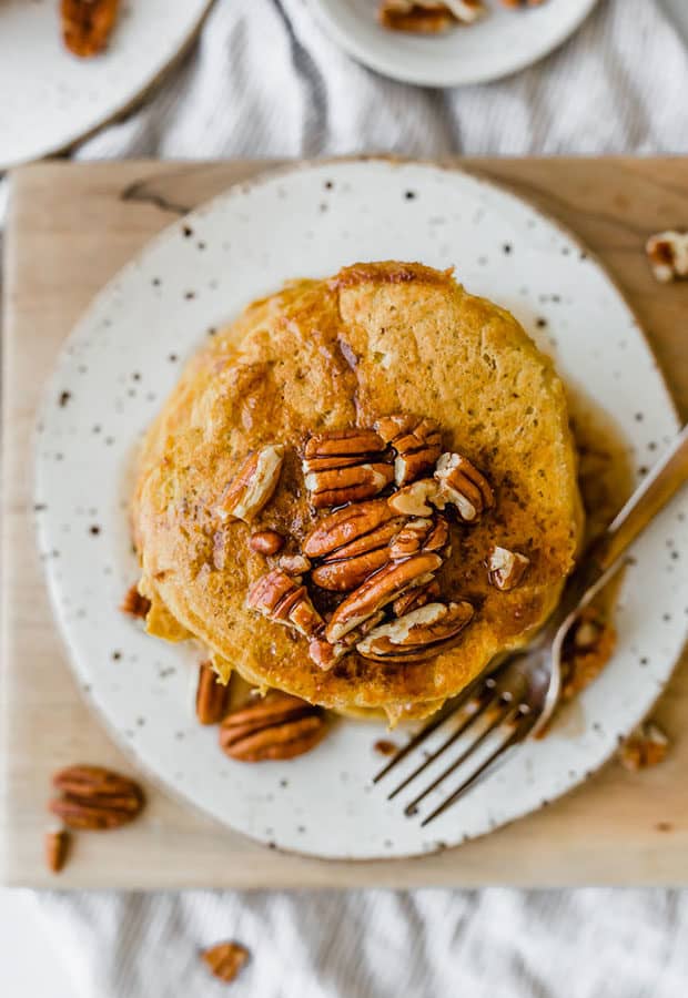 Overhead photo of pumpkin pancakes recipe topped with pecans and homemade syrup.