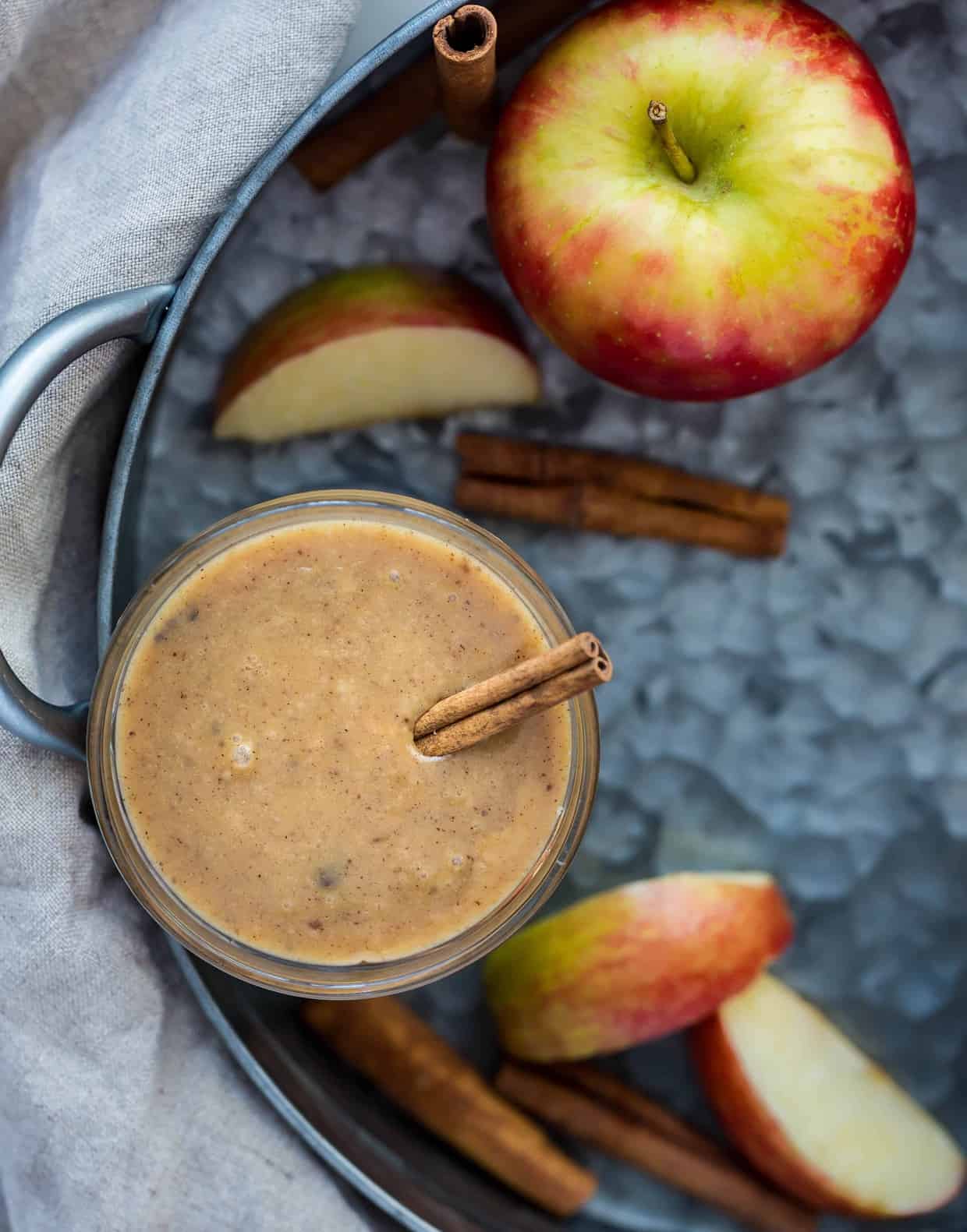 A jar of caramel apple dip with a cinnamon stick in the dip.