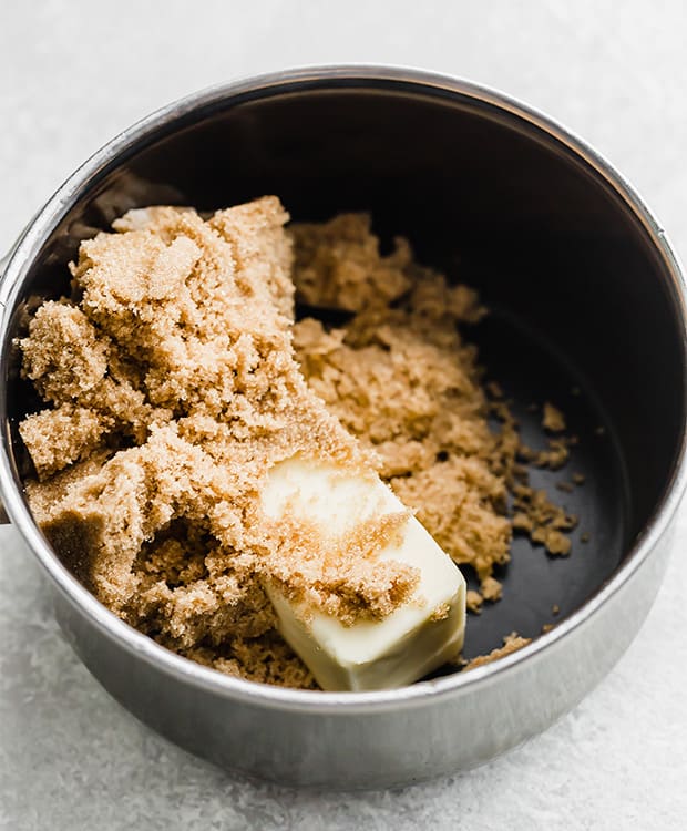 A saucepan with a cube of butter and brown sugar in it.