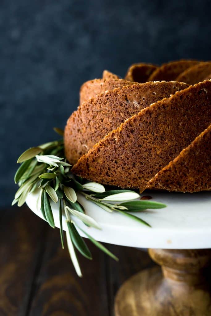 Close up of a gingerbread bundt cake, made in a spiral cake pan, with olive branches at the base of the cake.