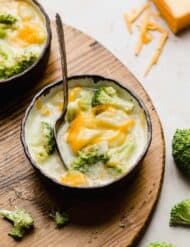 A bowl of Broccoli Potato Soup on a wooden board.
