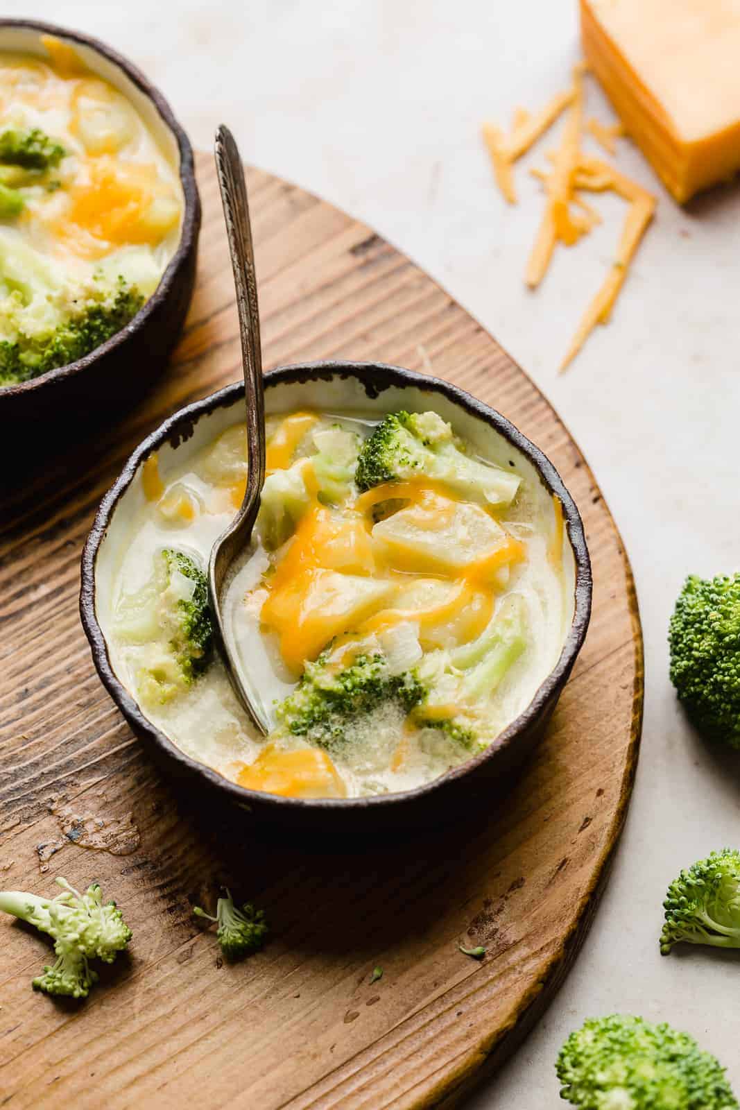 A bowl of Broccoli Potato Soup on a wooden board.