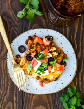 Mexican Lasagna garnished with olives, tomatoes, and cilantro.