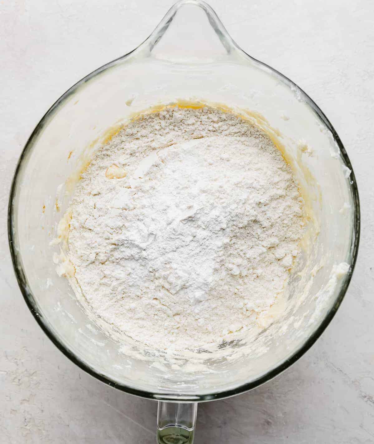 Flour and baking powder in a glass bowl on a gray background.