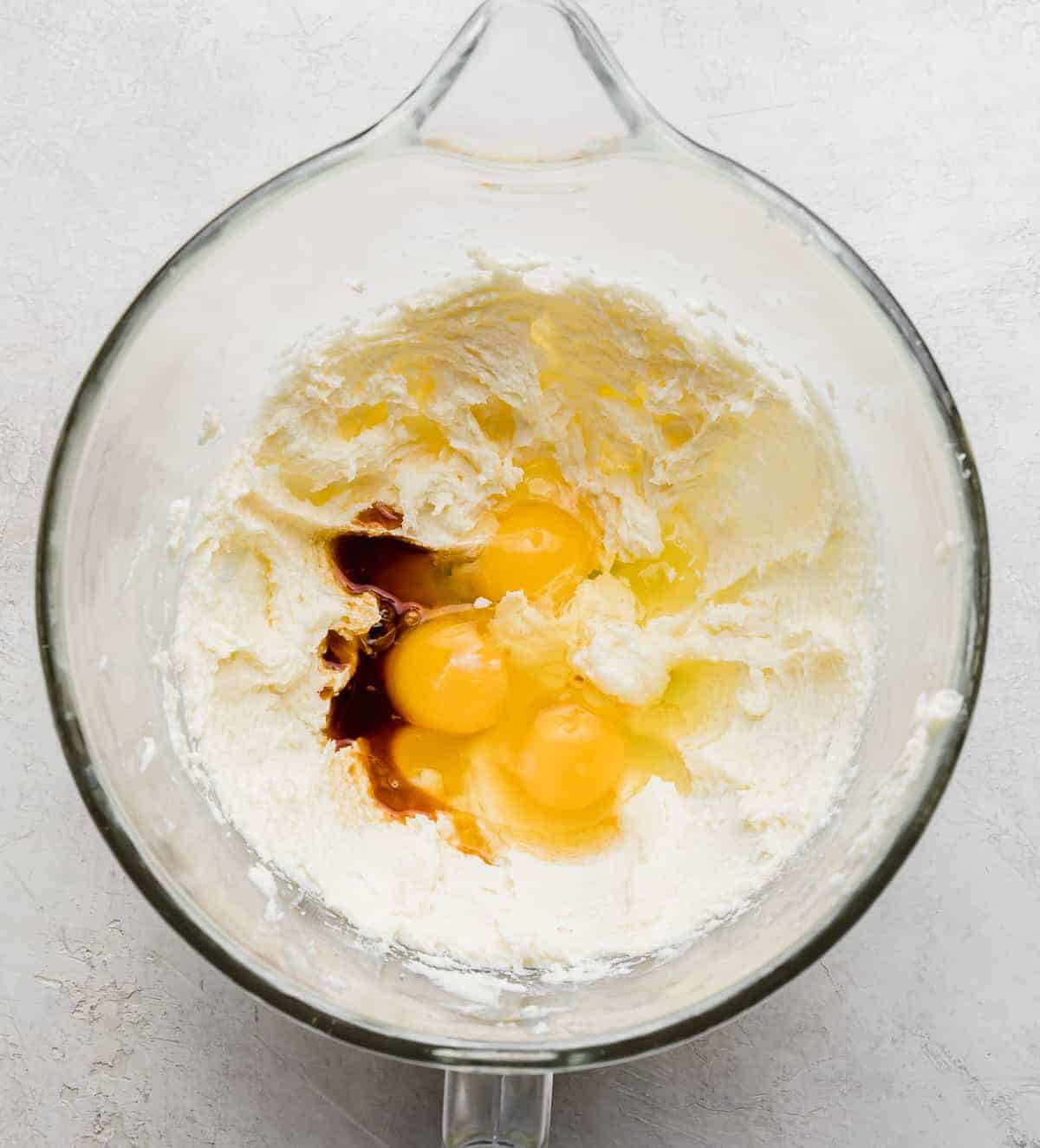 A glass bowl with creamed butter and sugar, eggs, and vanilla.