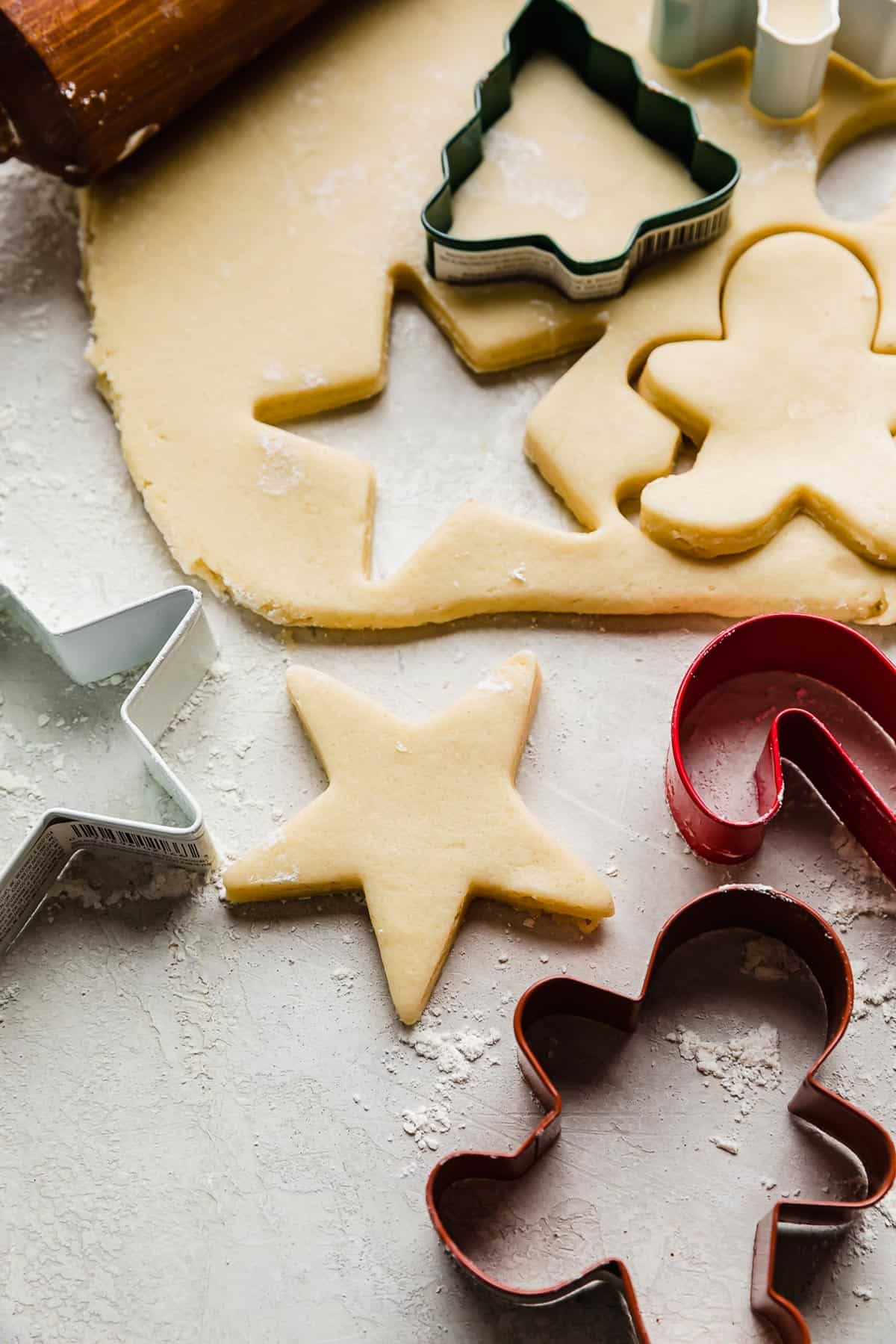 Sugar cookie dough rolled out on a gray surface with a star shape cut out from the dough.