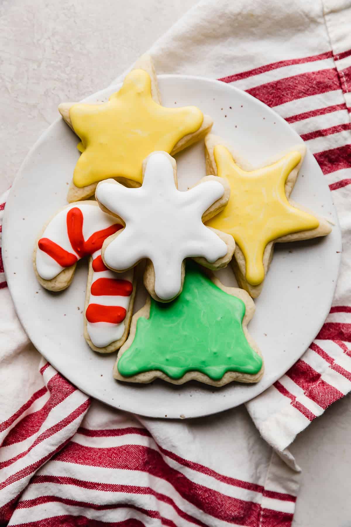 Sugar cookies cut into stars, candy cane, tree, and snowflake each topped with royal icing.