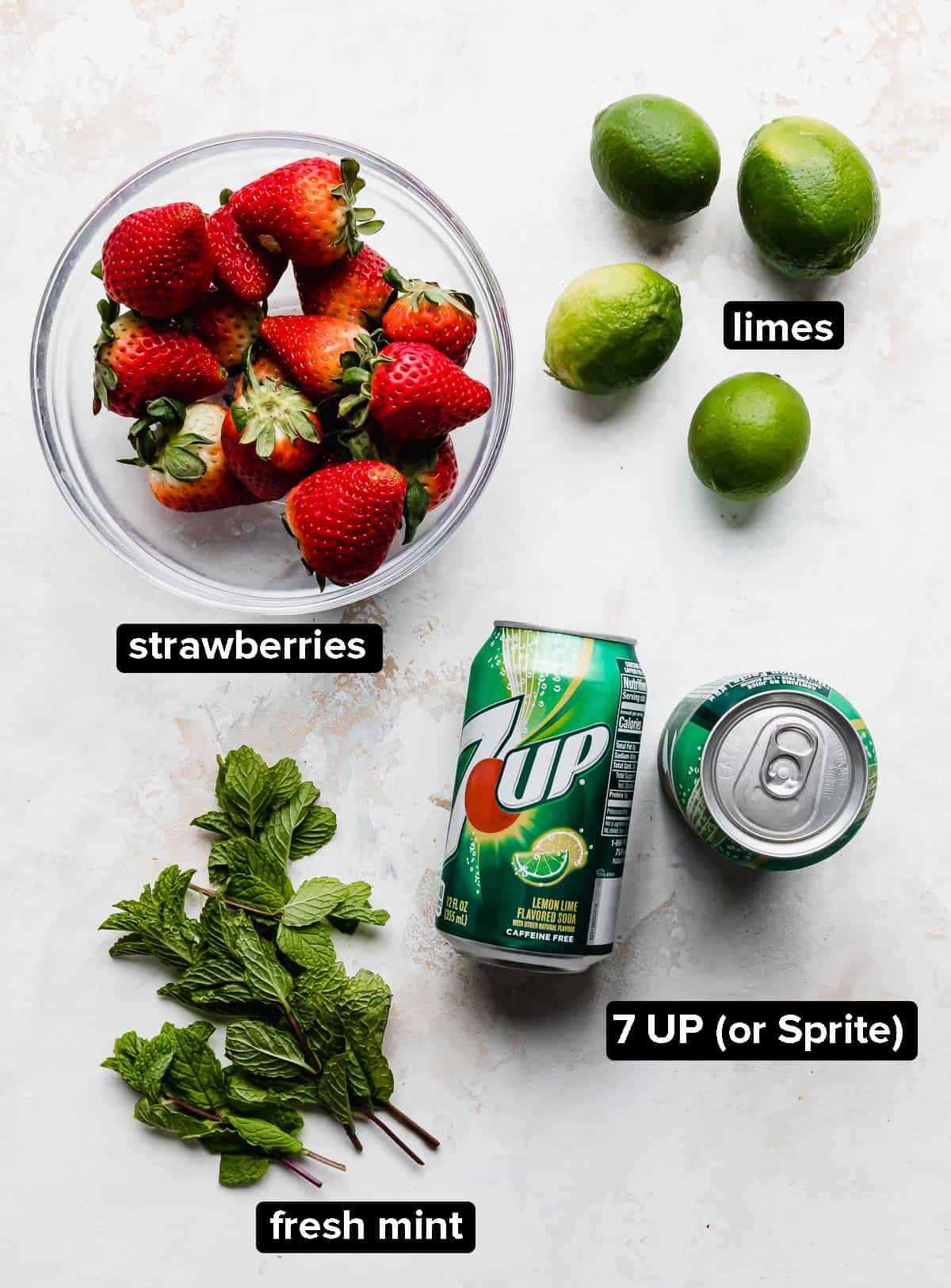 Strawberry Mocktail ingredients on a white background: limes, strawberries, mint, and Sprite or 7 UP.