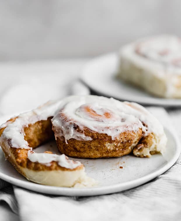 A cinnamon roll being on raveled on a plate.