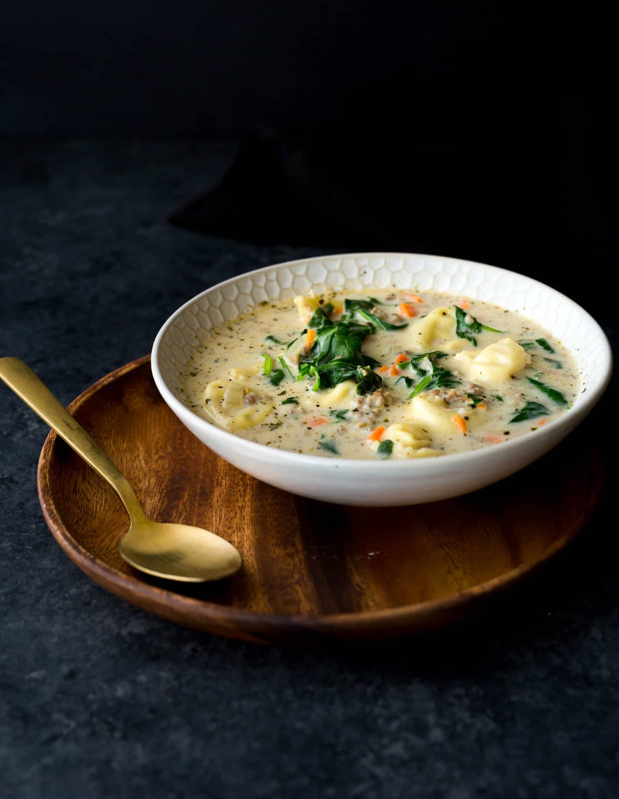 Side angle of a bowl of sausage tortellini soup.