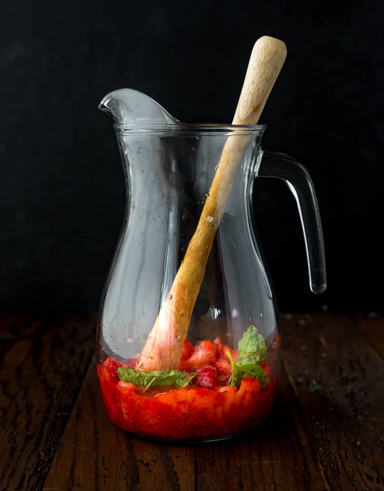 Glass pitcher with strawberries and mint leaves. 