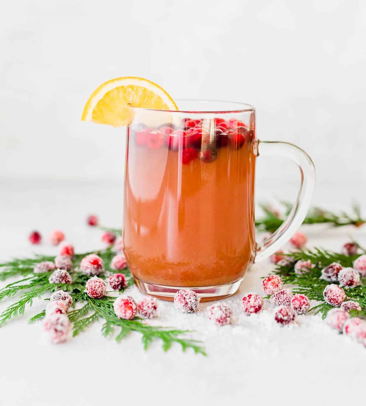 Cranberry Apple Cider with sugared cranberries at the base of the mug.