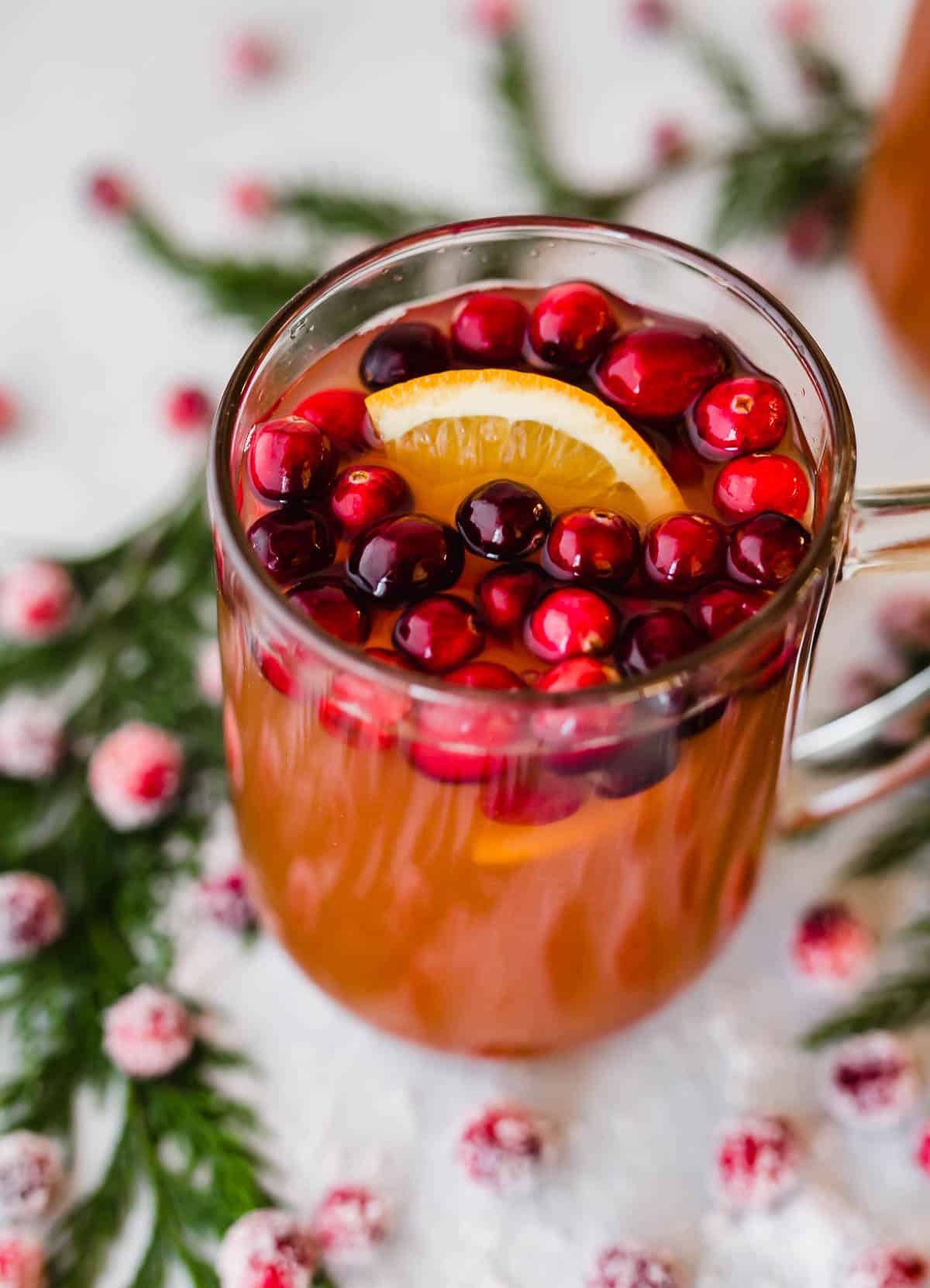 Overhead photo of Cranberry Apple Cider in a glass mug with lots of fresh cranberries in the cup too.