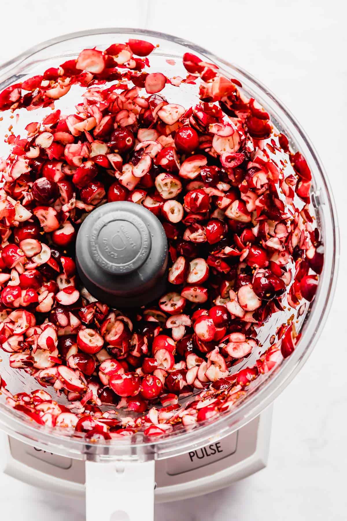 Chopped fresh red cranberries in a food processor for making cranberry salsa.
