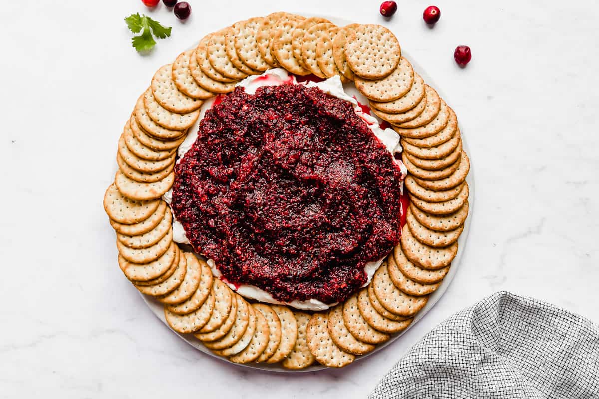 Cranberry Cream Cheese Dip topped with a fresh cranberry salsa surrounded by round crackers.
