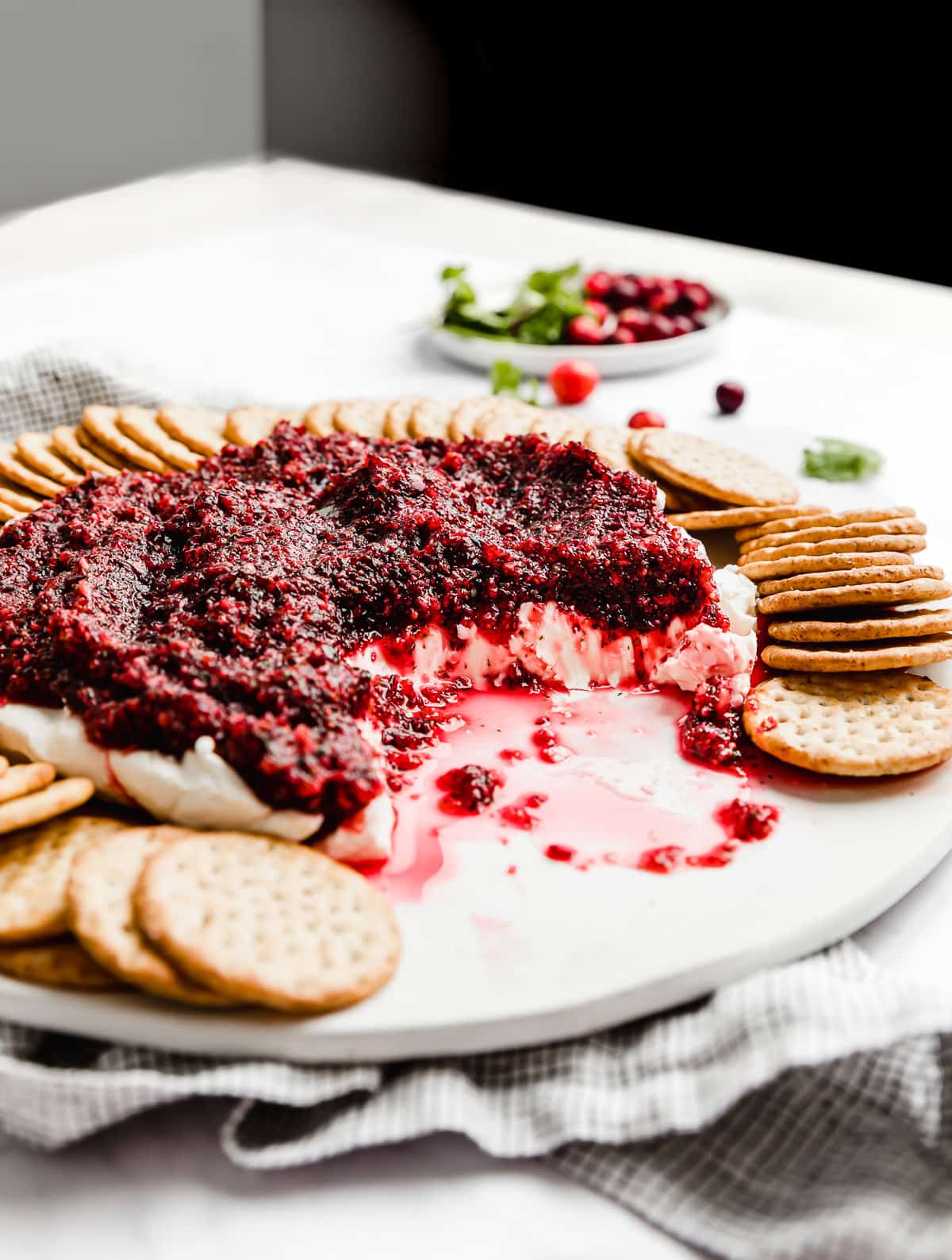 Cranberry Cream Cheese Dip on a white plate surrounded by round crackers. 