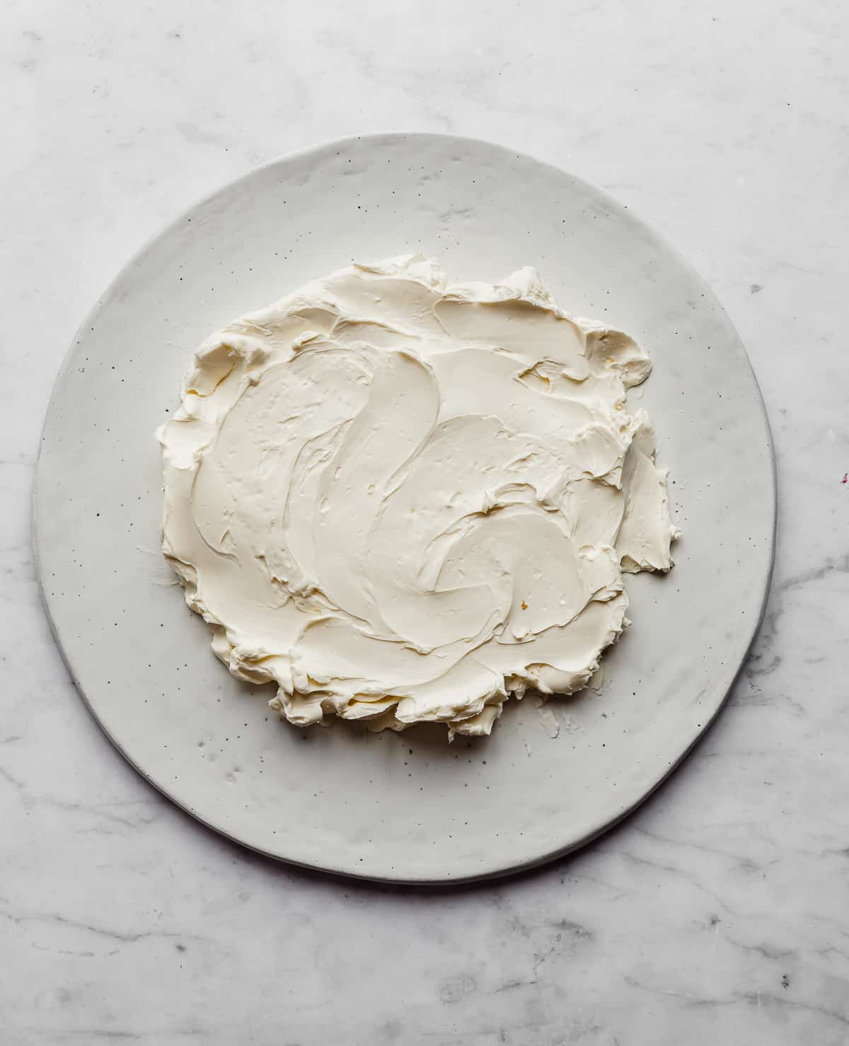 Cream cheese spread into a circle on a white plate.