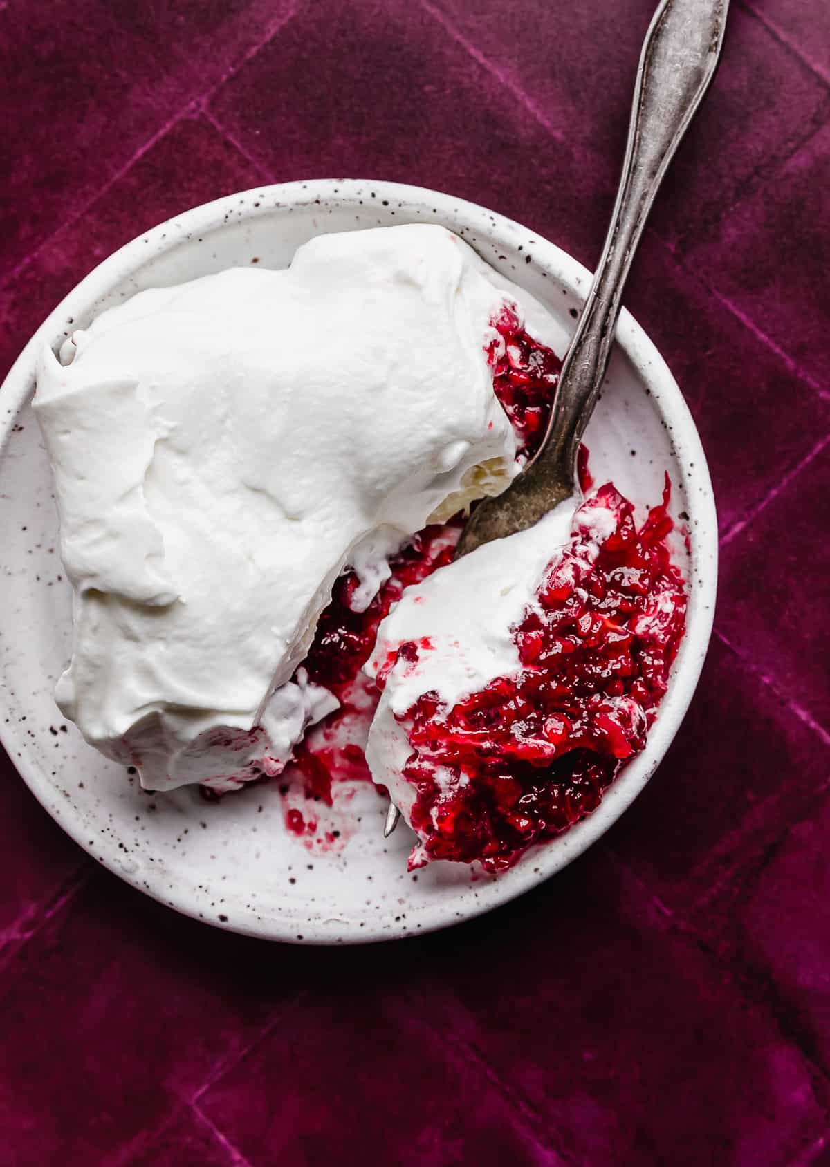 Christmas Pomegranate Jell-O on a white plate with a fork cutting into it.