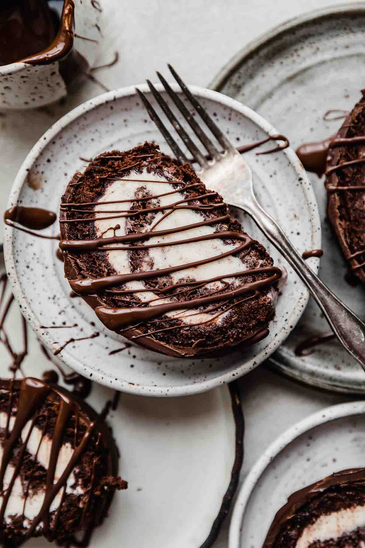 Ice Cream Cake Roll on a white plate with a metal fork next to the cake roll.