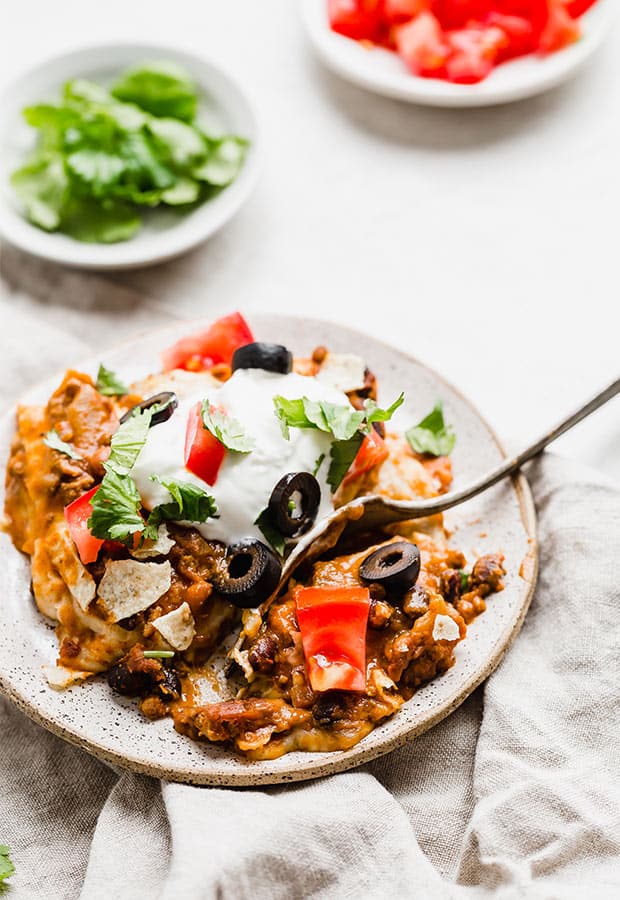 Mexican Lasagna topped with sour cream, cilantro, tomatoes, and olives.