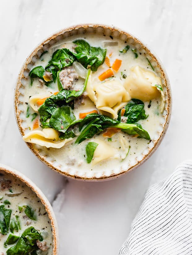 A bowl of sausage and tortellini soup.