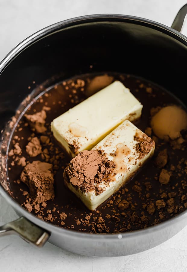 A sauce pan with two cubes of butter, water, and cocoa powder; for making Texas sheet cake.