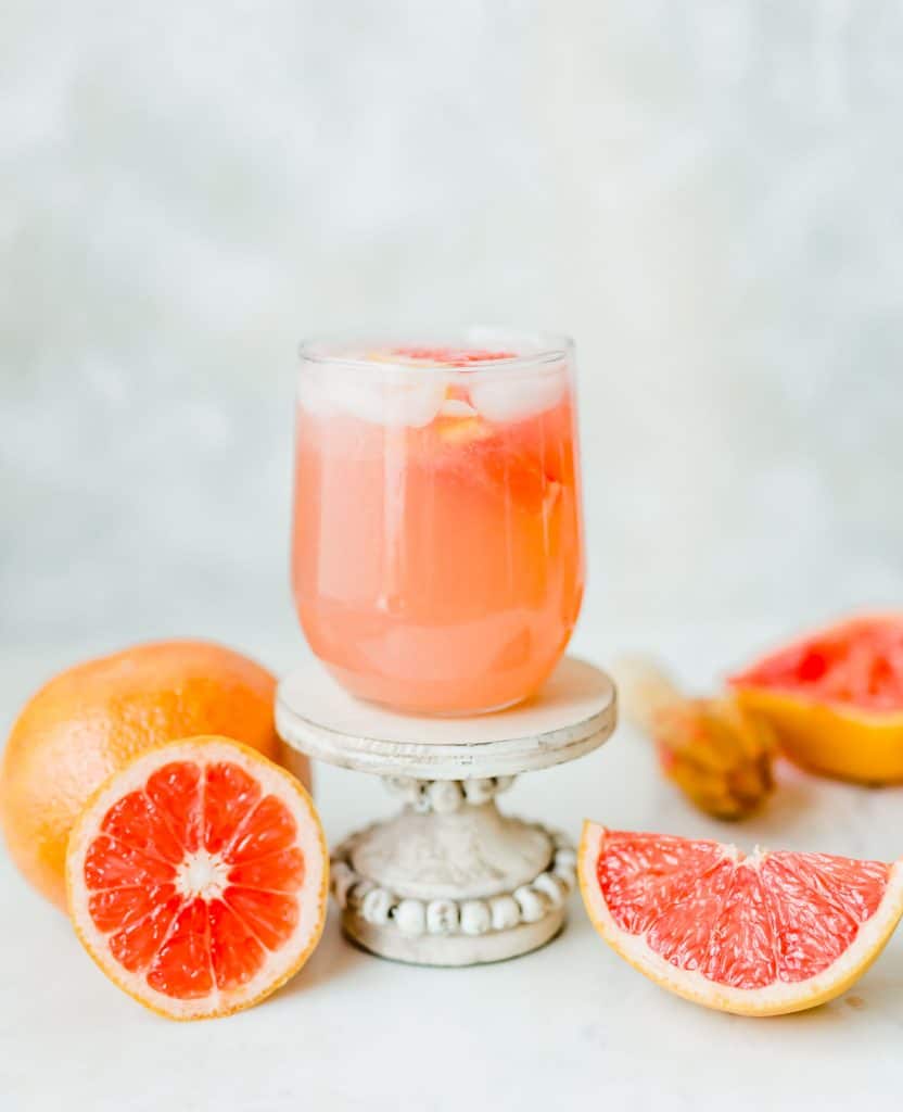 Grapefruit Italian Soda in a clear glass, with grapefruit surrounding the drink.