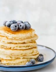 Fluffy homemade buttermilk pancakes from scratch, topped with frozen blueberries.