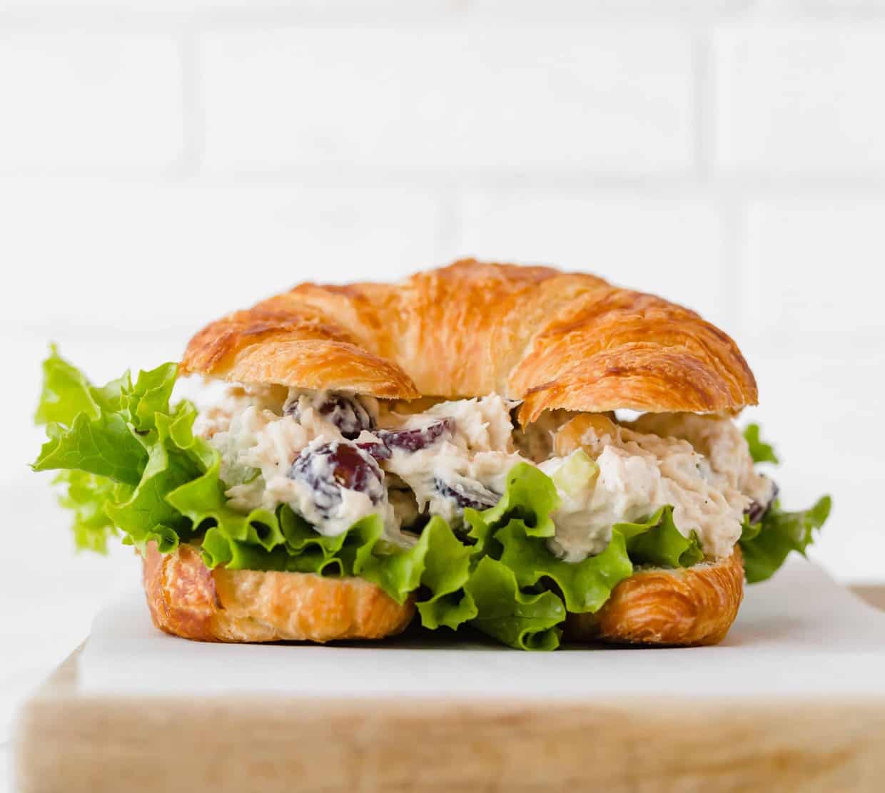 Chicken Salad Sandwich with leafy green lettuce on a croissant. 