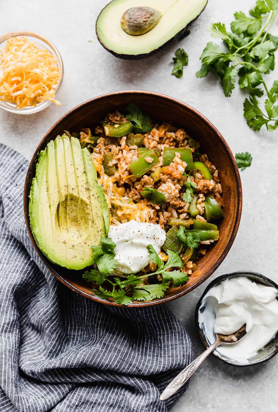 Deconstructed Stuffed Peppers in a bowl with sour cream, cilantro, and avocado for garnish.