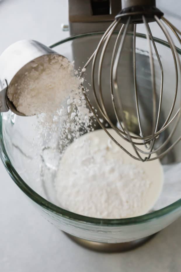 Powdered sugar being dumped into a kitchen aid bowl. 