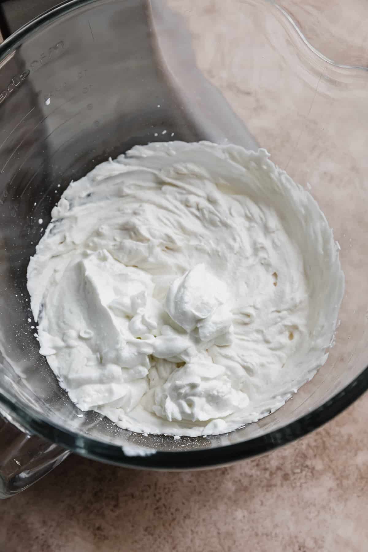 A glass bowl with Greek yogurt and whipped cream.