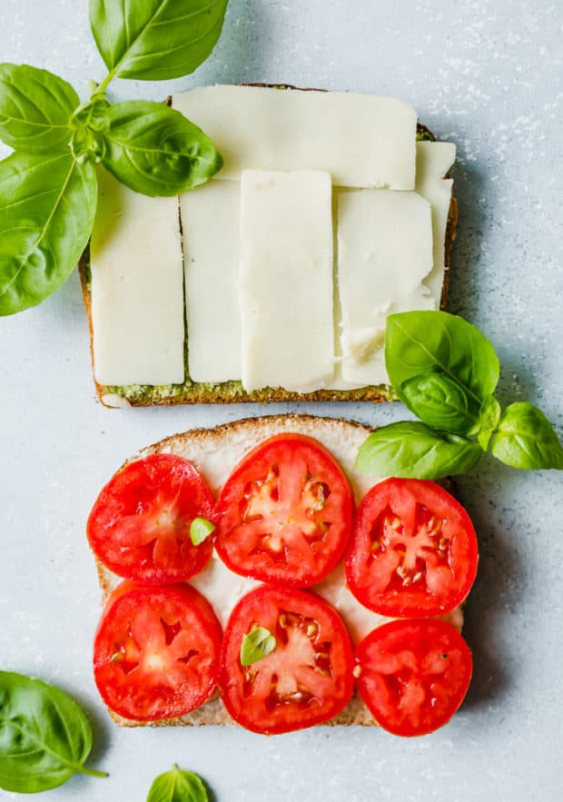 Two slices of bread, one slice covered in sliced mozzarella and the other with 6 slices of fresh tomatoes.